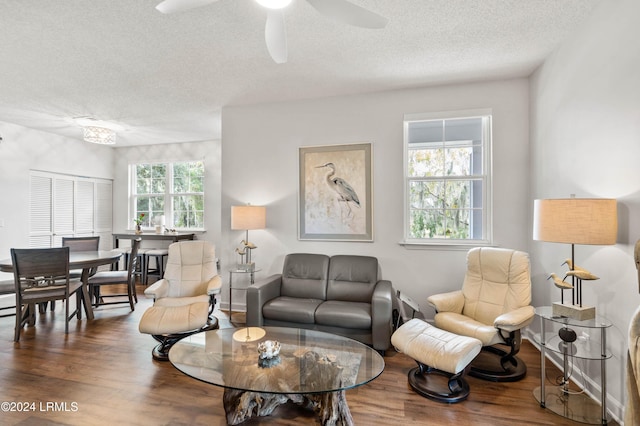 living room with ceiling fan, plenty of natural light, dark hardwood / wood-style floors, and a textured ceiling