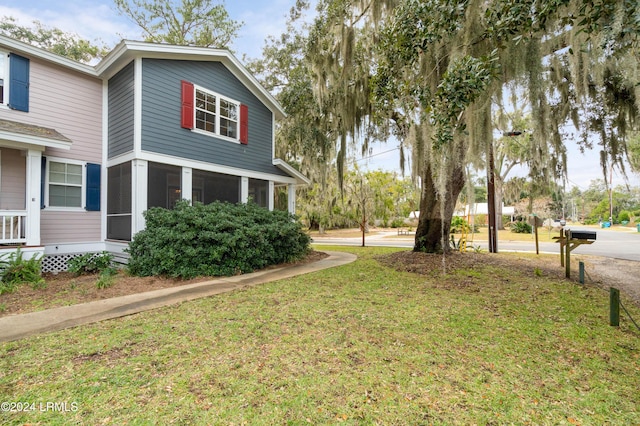 view of home's exterior with a yard and a sunroom