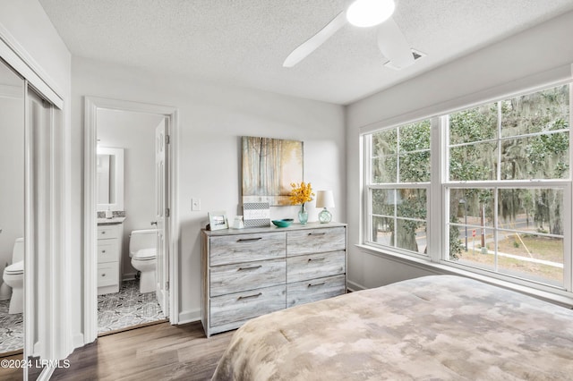 bedroom featuring dark hardwood / wood-style flooring, a textured ceiling, ceiling fan, and ensuite bathroom