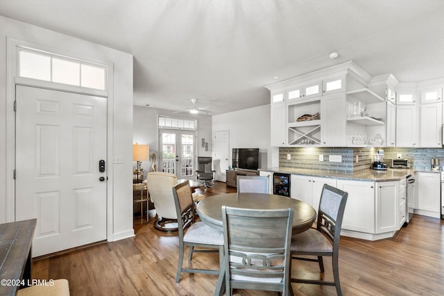 dining room featuring light hardwood / wood-style flooring, wine cooler, ceiling fan, a textured ceiling, and french doors