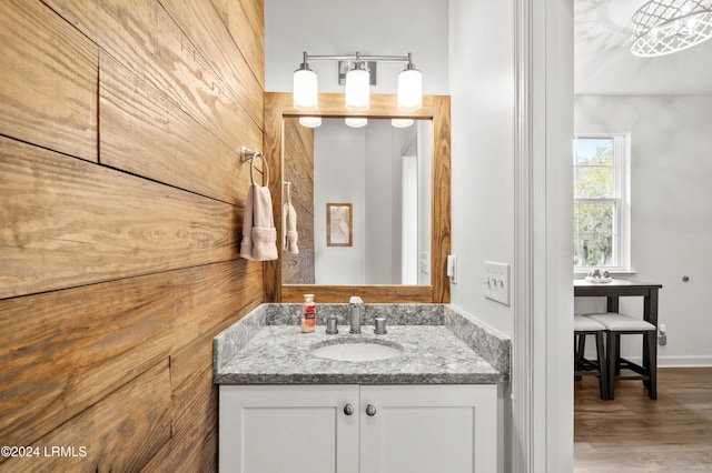 bathroom featuring vanity, wooden walls, and hardwood / wood-style floors