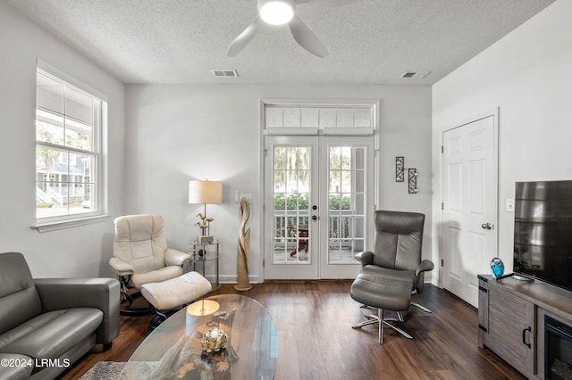 living area with dark wood-type flooring, a wealth of natural light, french doors, and a textured ceiling