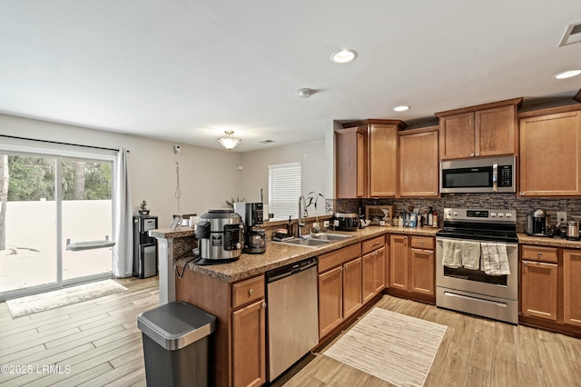 kitchen featuring tasteful backsplash, sink, kitchen peninsula, and appliances with stainless steel finishes