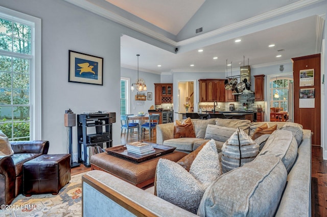 living room with vaulted ceiling, ornamental molding, a healthy amount of sunlight, and light hardwood / wood-style floors