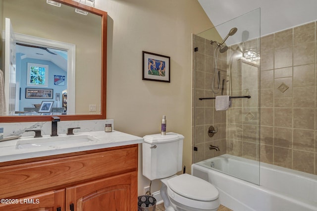 full bathroom with tiled shower / bath combo, vanity, vaulted ceiling, and toilet