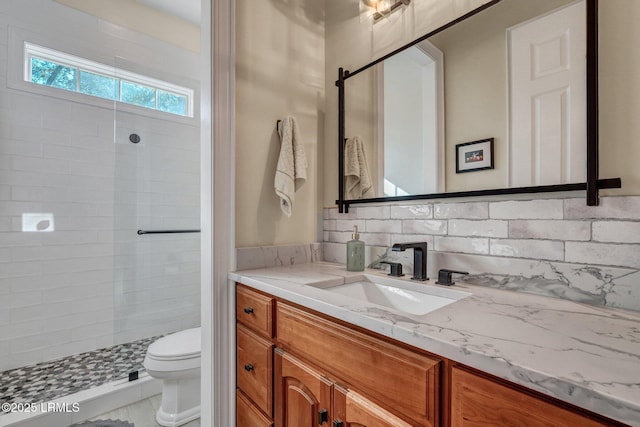 bathroom featuring tiled shower, vanity, toilet, and backsplash