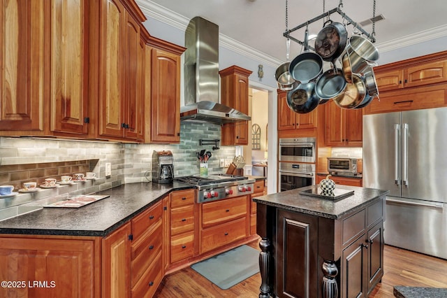 kitchen featuring crown molding, light hardwood / wood-style flooring, appliances with stainless steel finishes, a kitchen island, and wall chimney exhaust hood