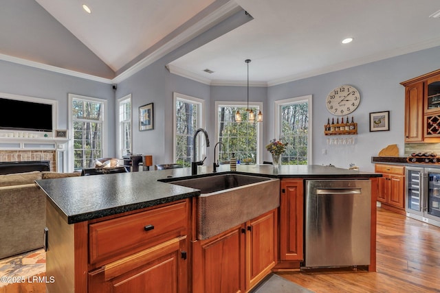 kitchen with sink, hanging light fixtures, stainless steel dishwasher, an island with sink, and light hardwood / wood-style floors