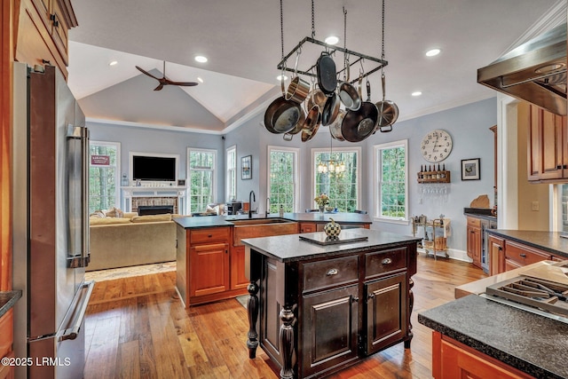 kitchen with sink, extractor fan, a healthy amount of sunlight, a kitchen island, and high end refrigerator