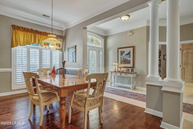 dining room featuring decorative columns, crown molding, and hardwood / wood-style flooring