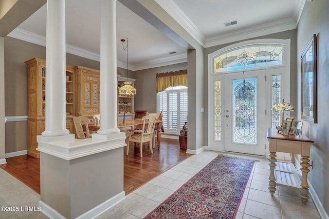 entryway with crown molding, light tile patterned floors, and ornate columns