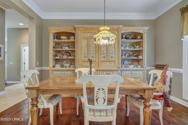 dining area with dark wood-type flooring, ornamental molding, and built in shelves