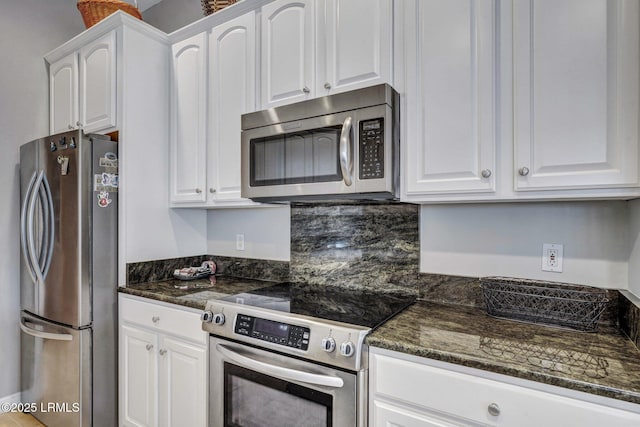 kitchen with white cabinetry, stainless steel appliances, and dark stone counters