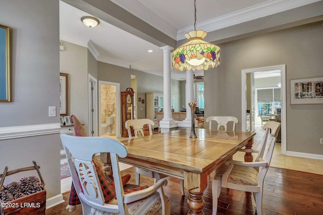 dining space featuring crown molding, hardwood / wood-style flooring, and decorative columns