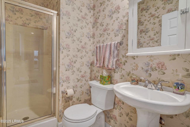 bathroom featuring sink, a shower with shower door, and toilet