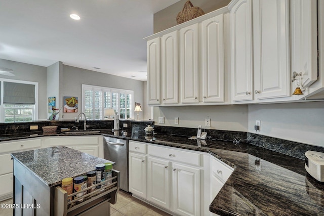 kitchen with white cabinetry, dark stone counters, kitchen peninsula, and sink