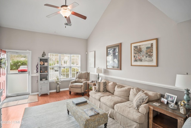 living area featuring light wood-style floors, ceiling fan, high vaulted ceiling, and baseboards