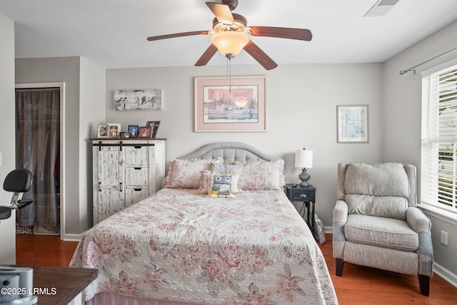 bedroom with visible vents, multiple windows, baseboards, and wood finished floors