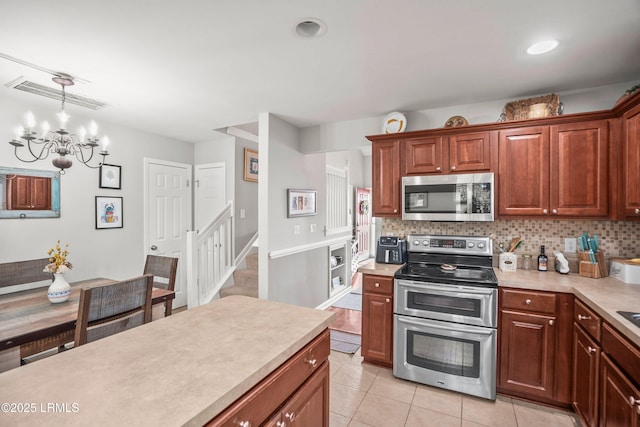 kitchen with appliances with stainless steel finishes, light countertops, visible vents, and decorative backsplash