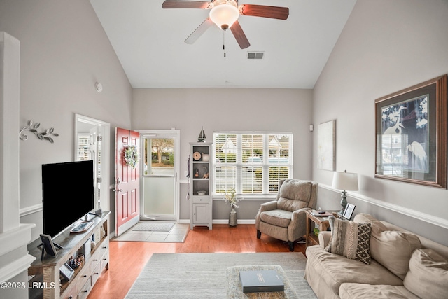 living area featuring ceiling fan, high vaulted ceiling, visible vents, baseboards, and light wood-style floors