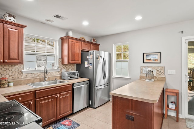 kitchen featuring stainless steel appliances, a sink, visible vents, light countertops, and tasteful backsplash