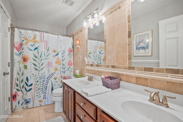 full bathroom with visible vents, a sink, toilet, and double vanity