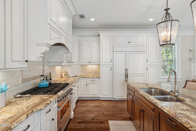 kitchen with high quality appliances, hanging light fixtures, sink, and white cabinets