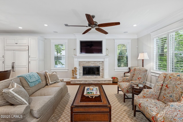 living room with crown molding, ceiling fan, and a fireplace