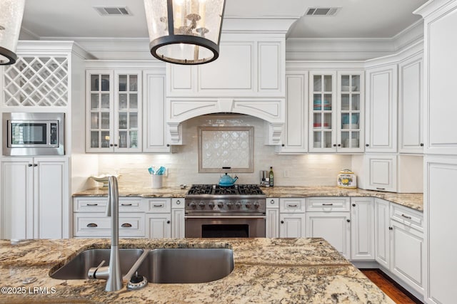 kitchen featuring sink, stainless steel appliances, light stone counters, tasteful backsplash, and white cabinets