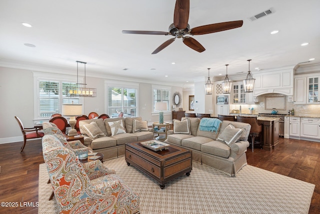 living room with crown molding, sink, dark wood-type flooring, and ceiling fan with notable chandelier