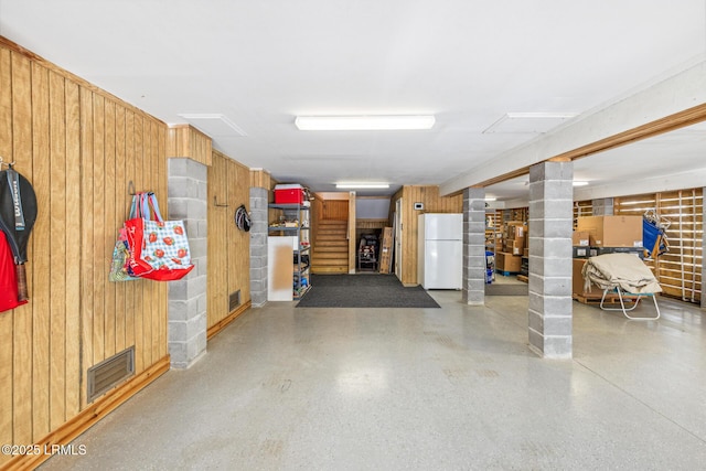 basement featuring wooden walls and white fridge