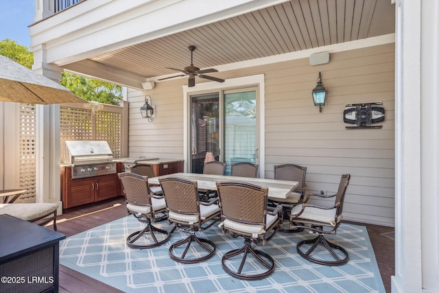 view of patio / terrace with area for grilling, a wooden deck, ceiling fan, and exterior kitchen