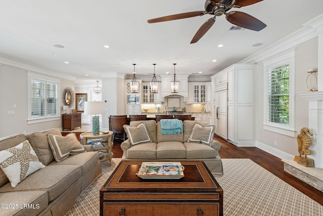 living room with ornamental molding, dark hardwood / wood-style floors, and ceiling fan