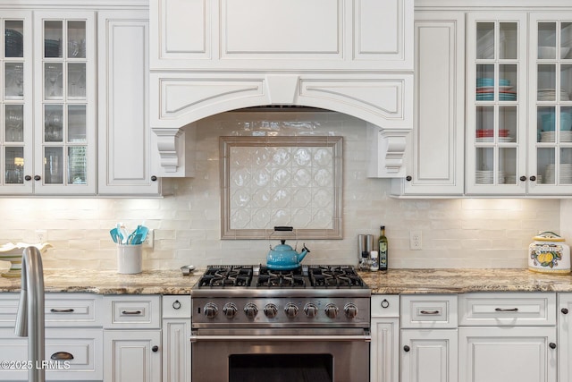 kitchen with white cabinetry, decorative backsplash, high end stainless steel range, and light stone countertops