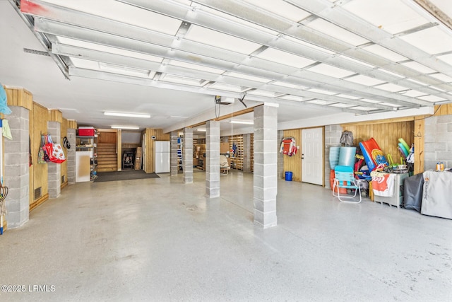 garage with a garage door opener and white fridge