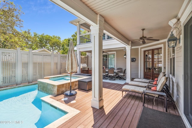 deck with french doors, ceiling fan, and a pool with hot tub