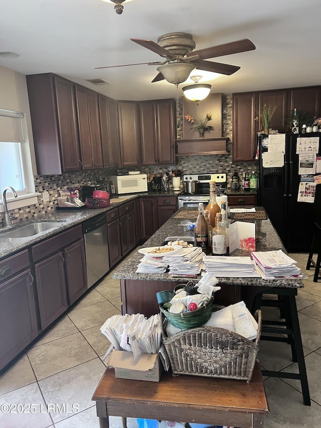 kitchen with dark brown cabinetry, stainless steel appliances, sink, and light tile patterned floors