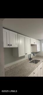 kitchen featuring white cabinetry and a sink