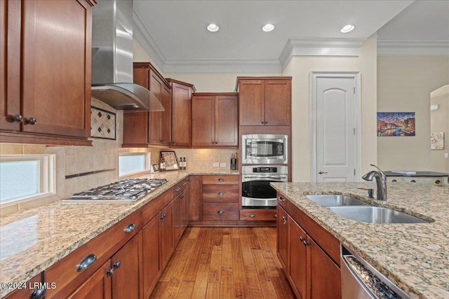 kitchen featuring sink, backsplash, stainless steel appliances, light stone counters, and wall chimney exhaust hood