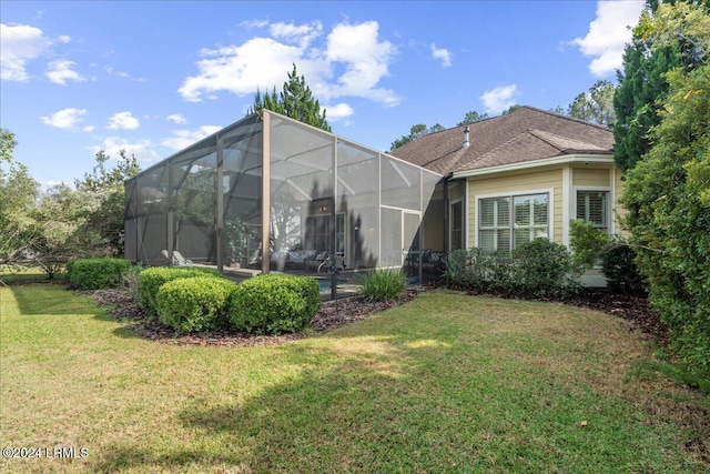 rear view of house featuring glass enclosure and a lawn