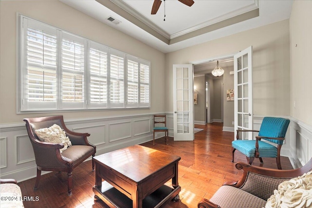 sitting room with hardwood / wood-style flooring, ornamental molding, ceiling fan, a raised ceiling, and french doors