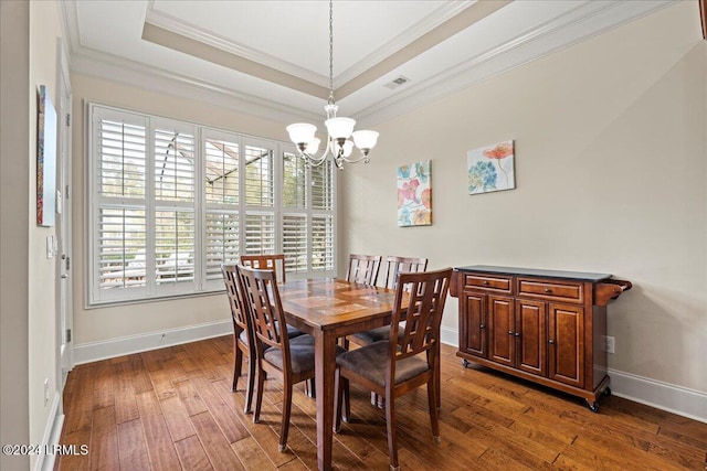 dining space featuring crown molding, dark hardwood / wood-style flooring, a raised ceiling, and a notable chandelier