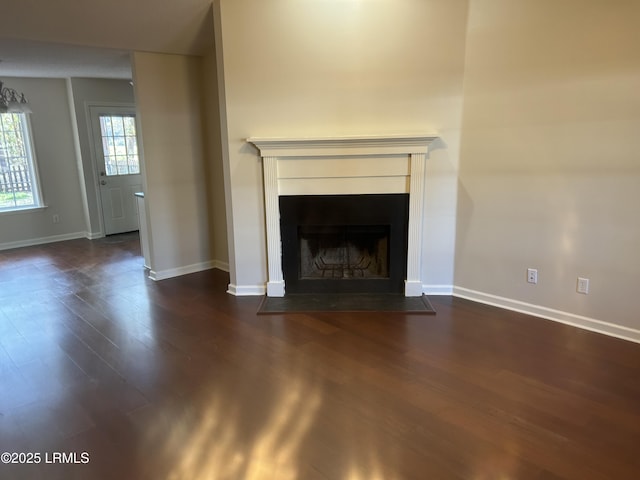 unfurnished living room with a fireplace with flush hearth, baseboards, and dark wood finished floors