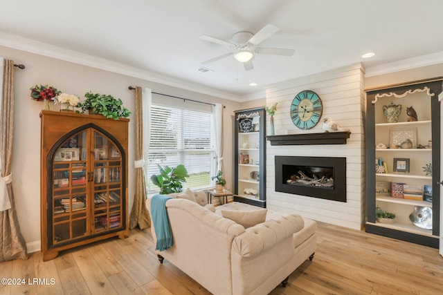 living room featuring crown molding, a large fireplace, and light hardwood / wood-style floors