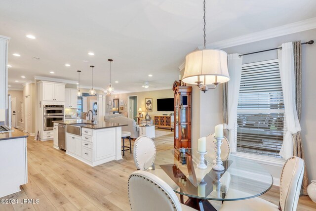 dining room with sink, crown molding, a wealth of natural light, and light wood-type flooring