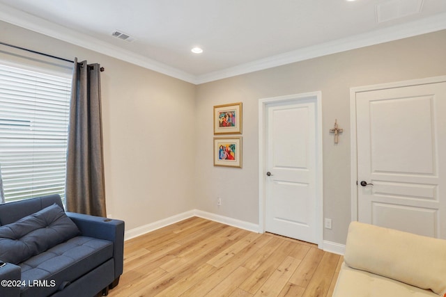 sitting room featuring ornamental molding and light wood-type flooring