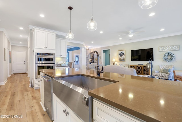 kitchen with pendant lighting, white cabinets, crown molding, stainless steel double oven, and light wood-type flooring