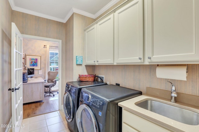 washroom with sink, crown molding, light tile patterned floors, cabinets, and washing machine and clothes dryer