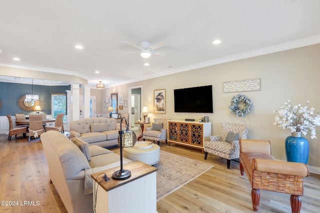 living room featuring ornate columns, crown molding, ceiling fan, and light wood-type flooring