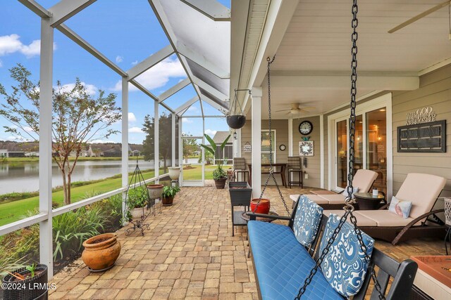 sunroom featuring beamed ceiling, ceiling fan, and a water view